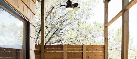 A covered outdoor seating area with wooden walls, a table, and two chairs.