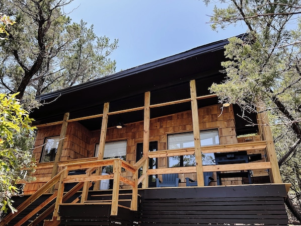 A wooden cabin with a balcony, windows, and a staircase. - The Canopy · Treetop Cabin, Hot Tub + Soaking Tub (Valley Mills)