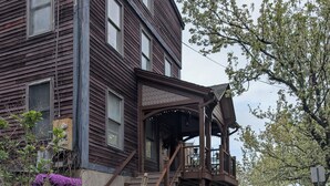 A two-story wooden house with a porch and a staircase leading to the second floor. - 146-7 AA. Gorgeous 2-bedroom apartment with AC in New London (New London)