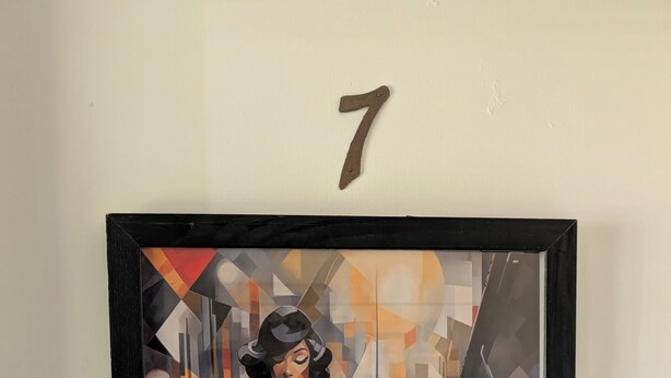 A framed artwork of a woman playing a piano, mounted on a wall with a number 7 above it. - 146-7 AA. Gorgeous 2-bedroom apartment with AC in New London (New London)