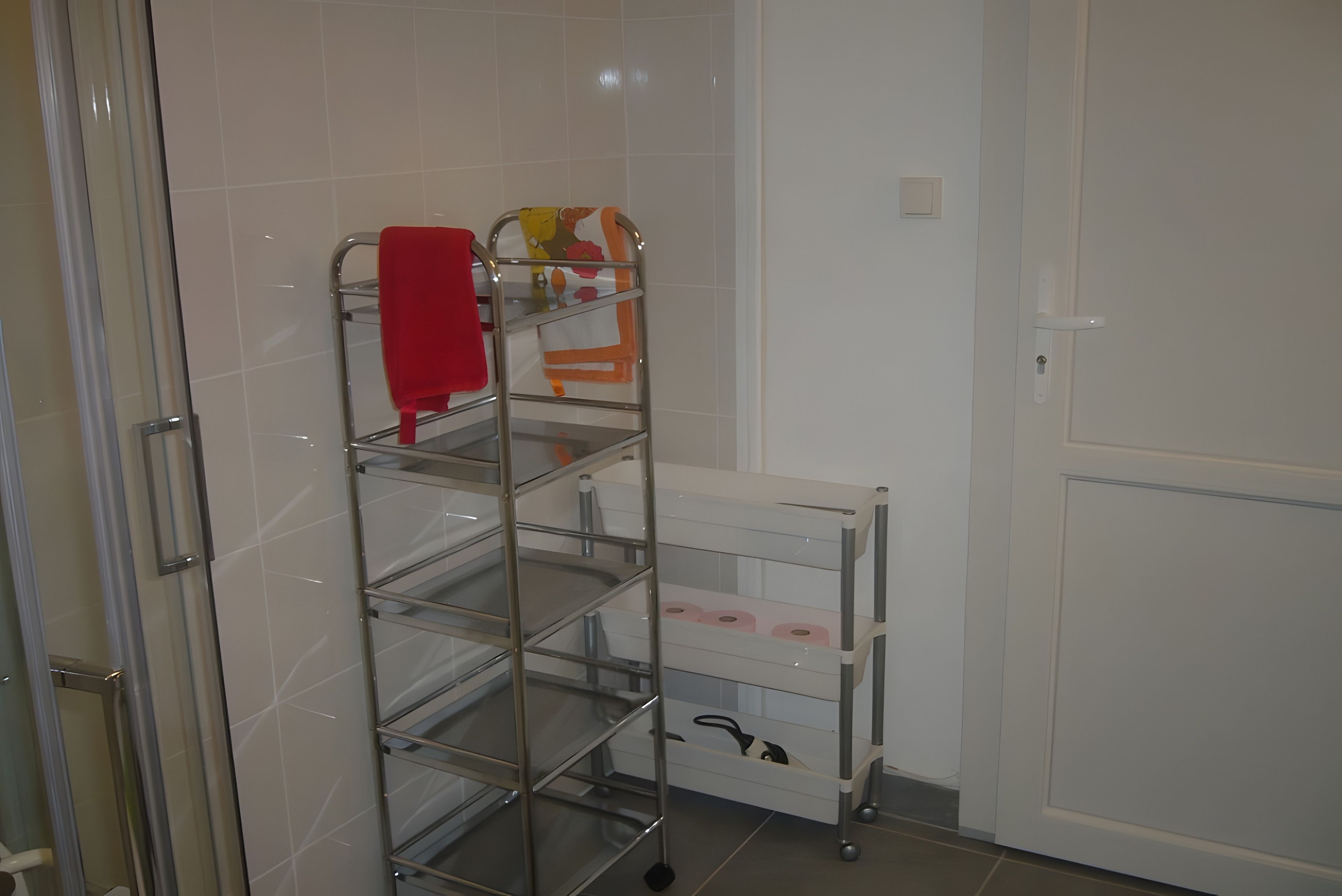 Ein Badezimmer mit einem Metallregal, das Handtücher und einen Toilettenpapierhalter enthält.