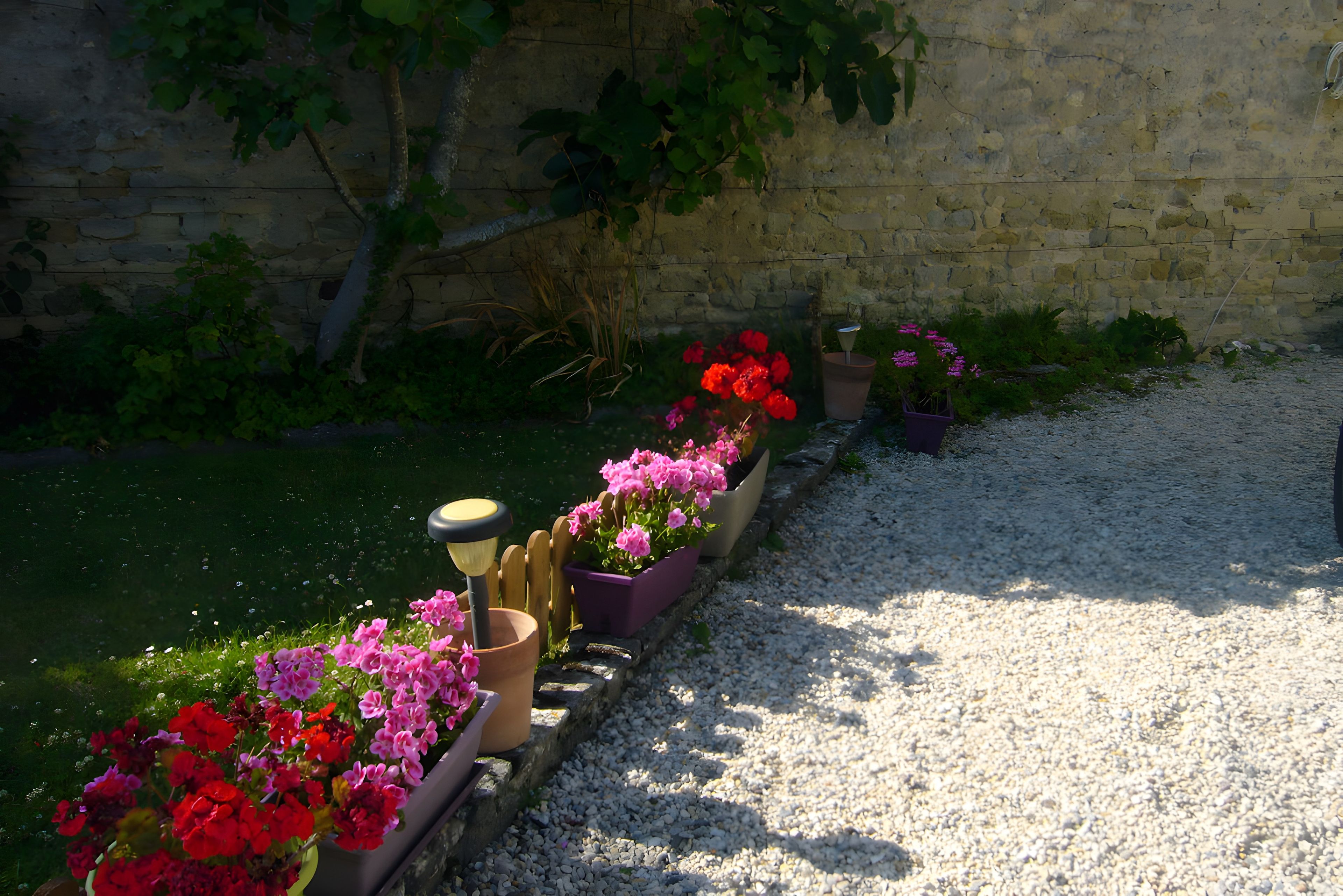 Ein Gartenweg mit Blumenbeeten und einer Steinmauer.