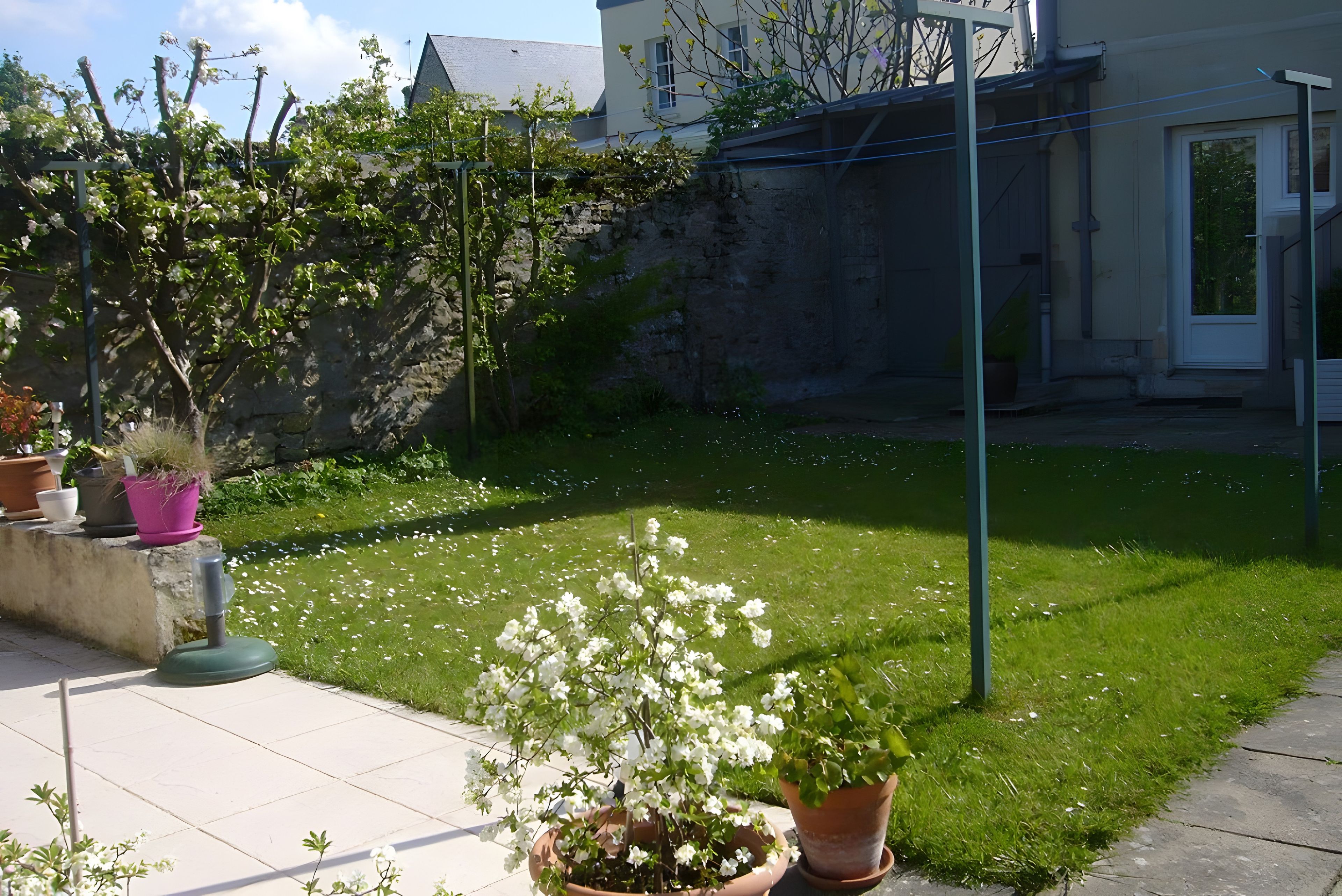 Un jardín bien cuidado con plantas en macetas variadas y un césped impecable.