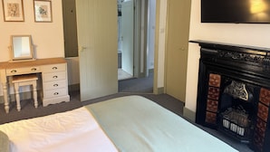 Ein Schlafzimmer mit Bett, Kommode, Spiegel und Kamin.