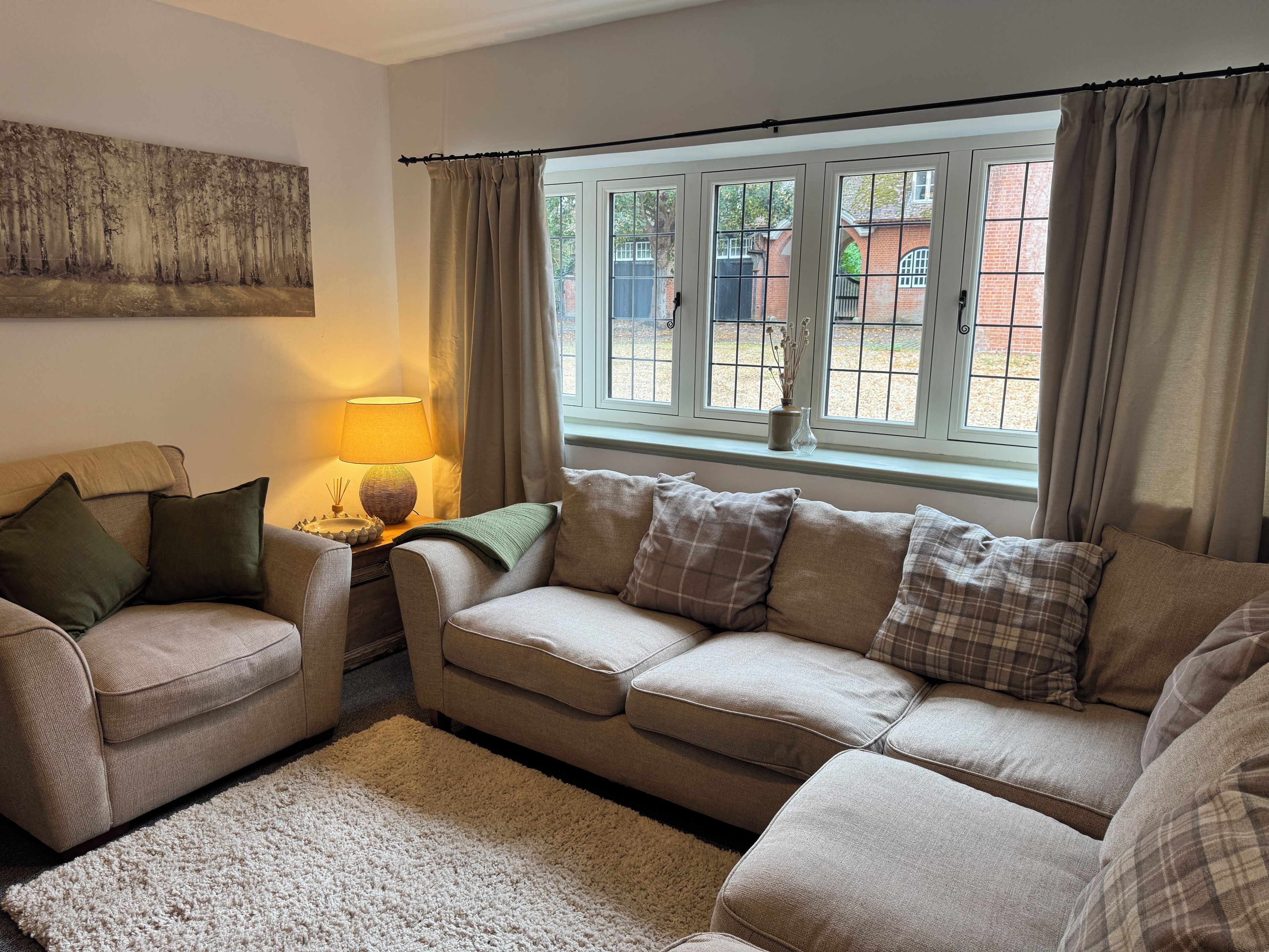 A living room with a beige sofa, a lamp, and a painting on the wall.