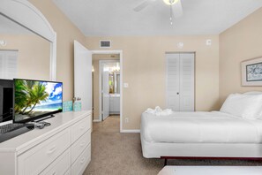 Quarto de hotel com uma cama, uma escrivaninha com computador, televisão e porta para um banheiro.