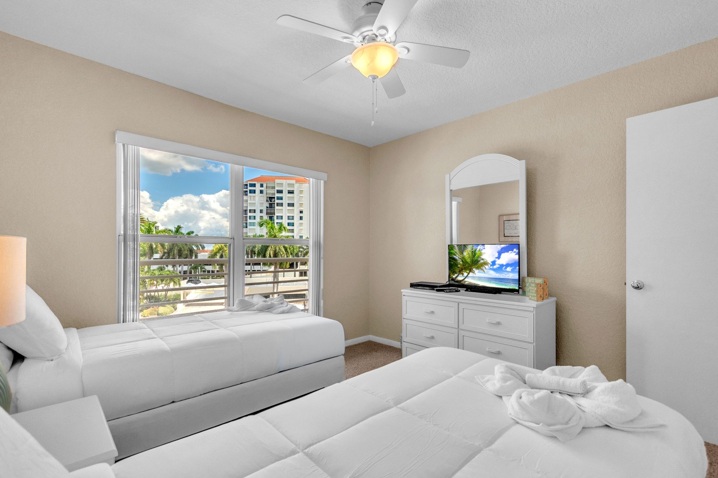 A hotel room with a bed, a dresser, a TV, and a ceiling fan.