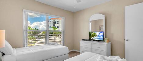 Una habitación de hotel con cama, tocador, televisor y ventilador de techo.