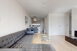 A modern living room with a grey sofa, a coffee table, and a television. - 1BR Flat w/Balcony Near Tube and London Stadium (London)