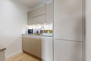 A modern kitchen with a microwave, kettle, and coffee maker on the countertop. - 1BR Flat w/Balcony Near Tube and London Stadium (London)