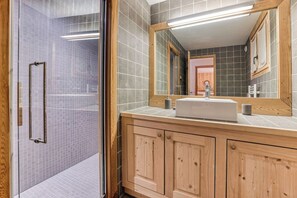 Une salle de bain avec une douche, un lavabo et un miroir.