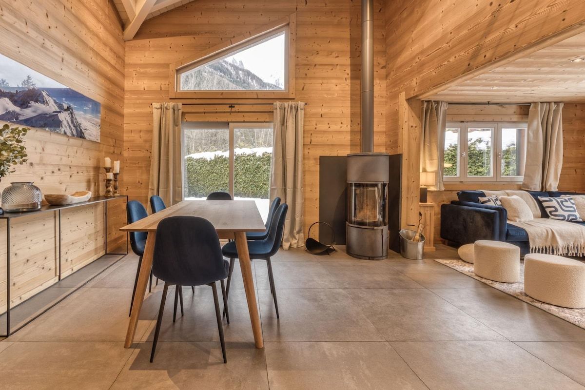 A wooden cabin interior with a dining area, a fireplace, and a sofa.