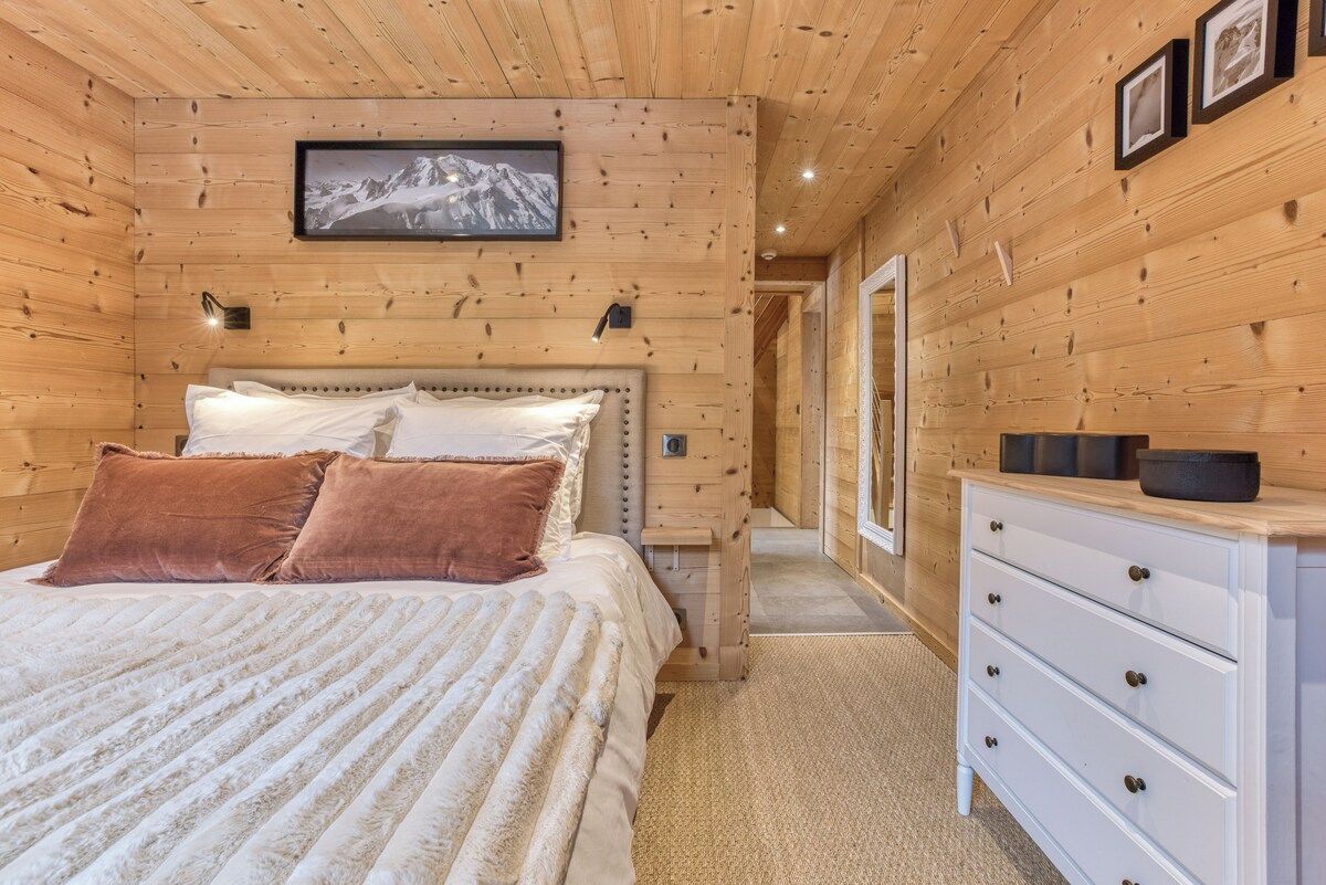 A wooden-paneled room with a bed, a dresser, and a framed picture on the wall.