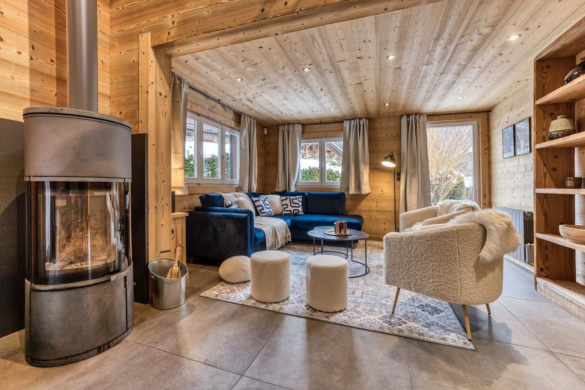 L’intérieur d’un chalet confortable, avec un poêle à bois, un canapé bleu, un fauteuil beige et une petite table.
