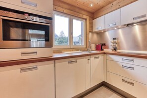 Eine moderne Küche mit Backofen, Fenster und einer Dunstabzugshaube aus Edelstahl.