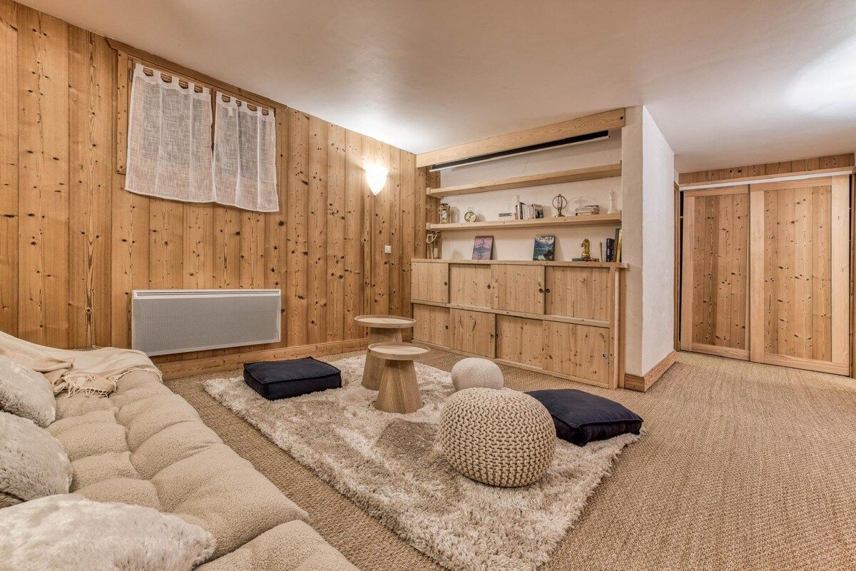 Een gezellige kamer met een houten wand, een bank, een vloerkleed en een plank met decoratieve spullen.