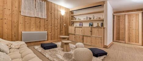 Een gezellige kamer met een houten wand, een bank, een vloerkleed en een plank met decoratieve spullen.