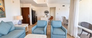 Un salon moderne comprenant un canapé, deux fauteuils, une table basse et un coin repas avec une table et des chaises.