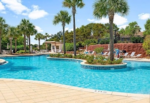 Piscina com espreguiçadeiras e palmeiras.
