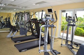 Ein Fitnessraum mit mehreren Landice L7 Laufbändern, einem digitalen Display und Blick auf Grünflächen.