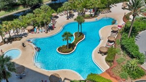 A large swimming pool with a curved design, surrounded by palm trees and lounge chairs. - Luau 2 6622/6624LO, New to Rentals, Pool Views, (Miramar Beach)