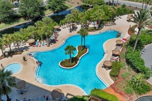 Ein großer Pool mit gewölbtem Design, umgeben von Palmen und Liegestühlen.