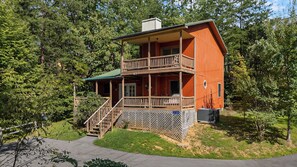 Eine zweistöckige Holzhütte mit Balkon, umgeben von Bäumen.