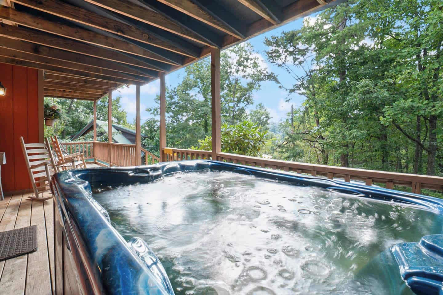 Un jacuzzi en una terraza de madera con vistas a árboles.