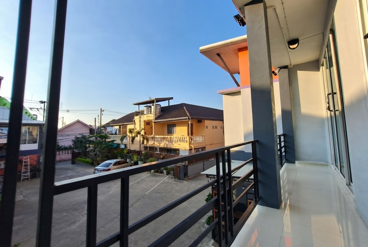 A residential balcony with a view of neighboring houses and a parked car.