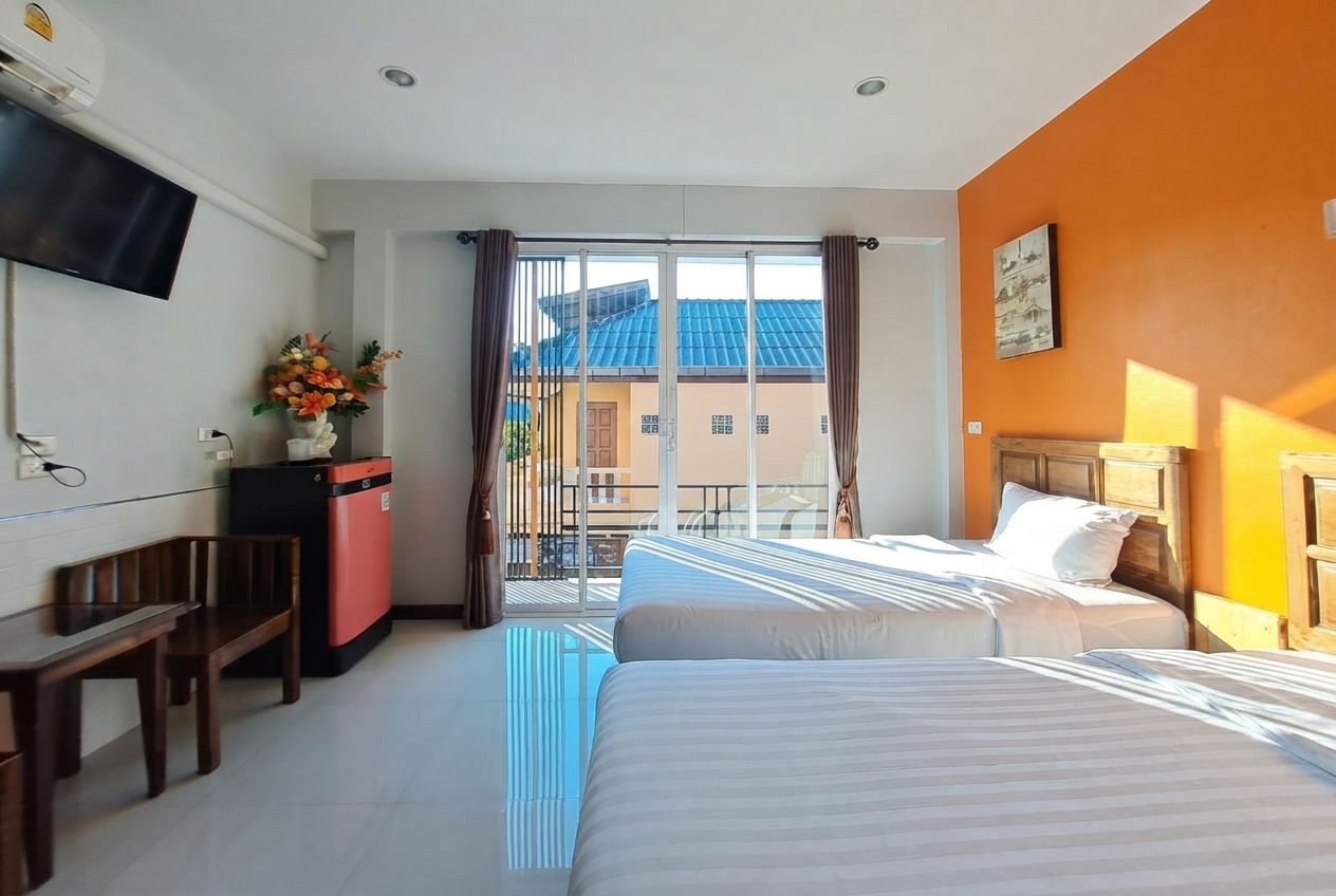 A hotel room with a bed, a desk, a TV, and a view of the outside.