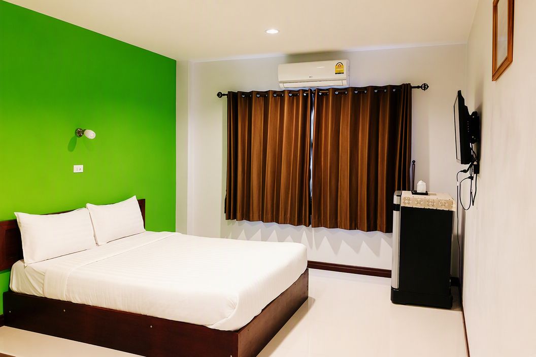 Una habitación de hotel con cama, aire acondicionado, televisor y cortina.