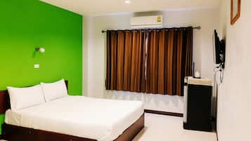 Una habitación de hotel con cama, aire acondicionado, televisor y cortina.