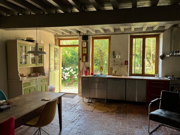 A kitchen with a dining area, a large window, and a view of the garden.
