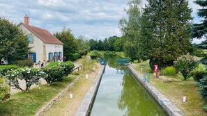 A narrow canal with a house on one side and trees on the other.