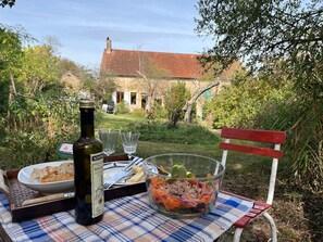 An outdoor dining setup with a bottle, salad, and bread on a checkered tablecloth.