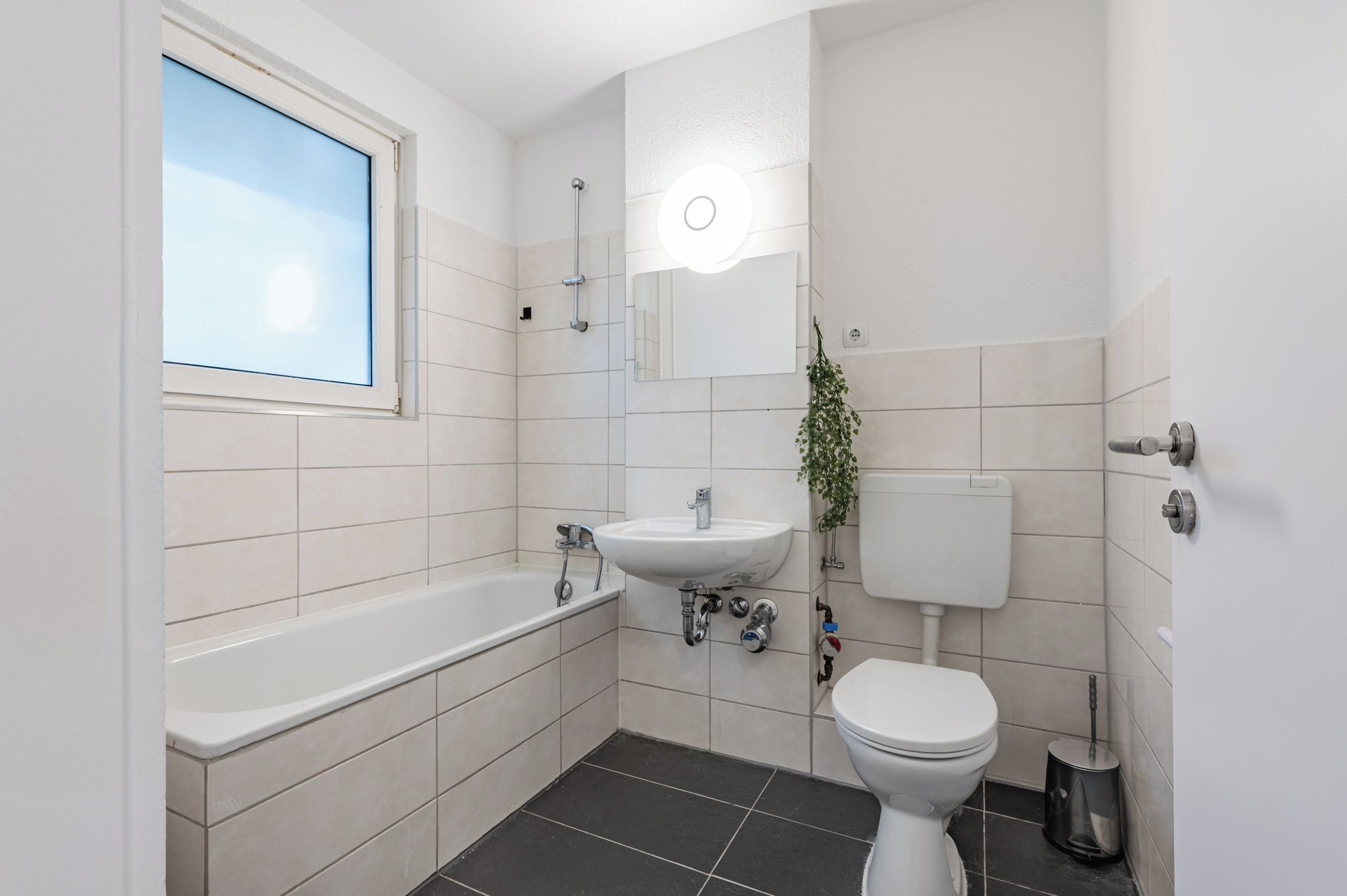 Un baño moderno con bañera, lavamanos, inodoro y ventana.