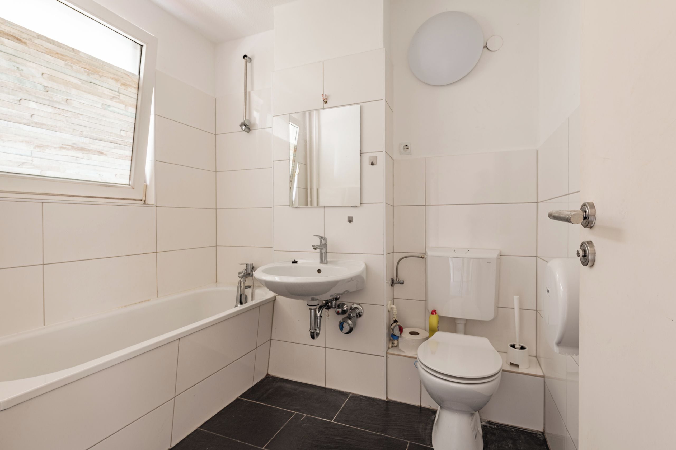 A bathroom with a bathtub, sink, toilet, and a mirror.