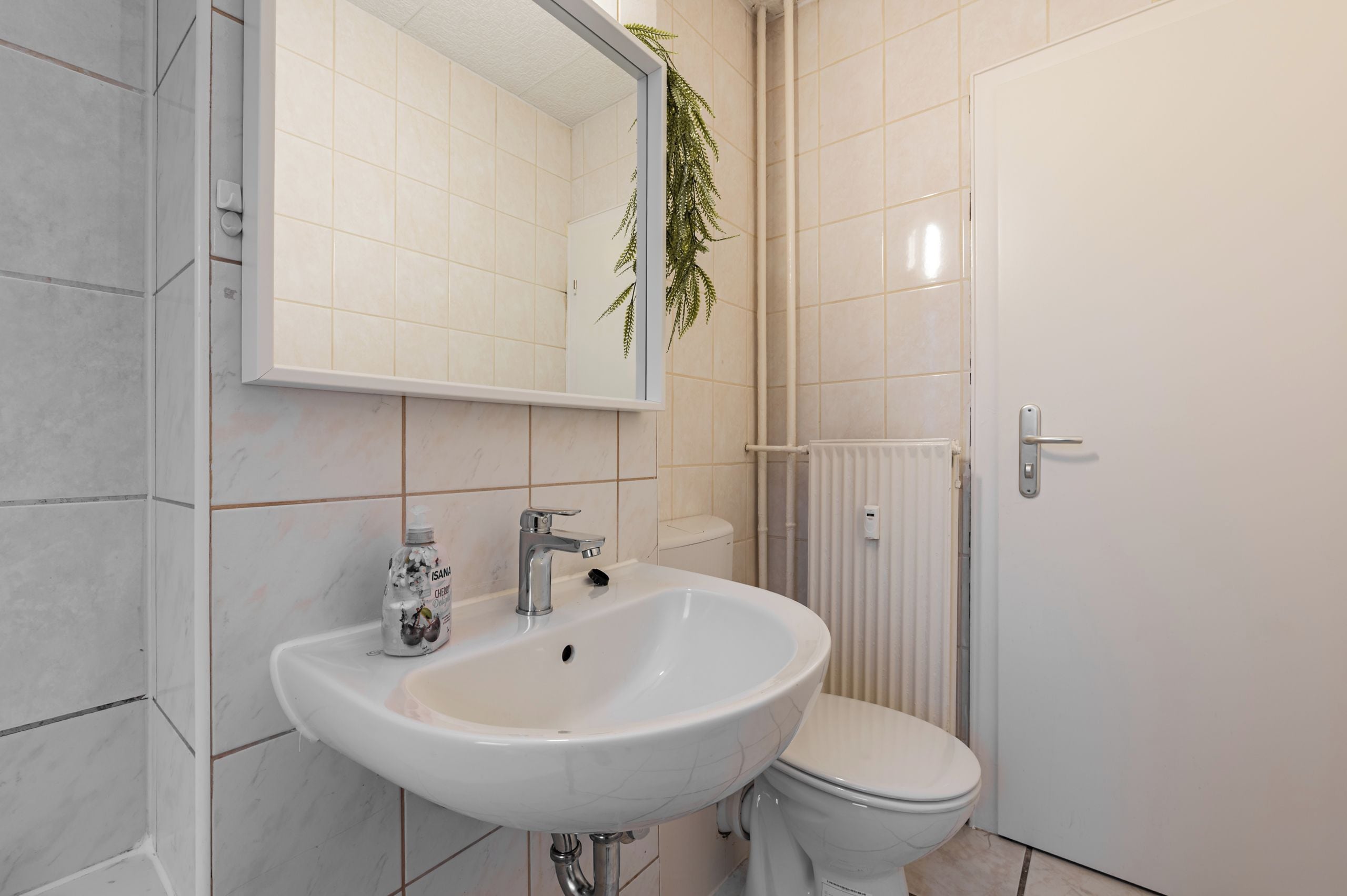 Ein Badezimmer mit Waschbecken, Spiegel, Toilette und Heizkörper.