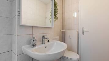 Ein Badezimmer mit Waschbecken, Spiegel, Toilette und Heizkörper.