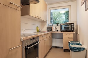 A compact kitchen with a built-in oven, microwave, and a window above the sink.