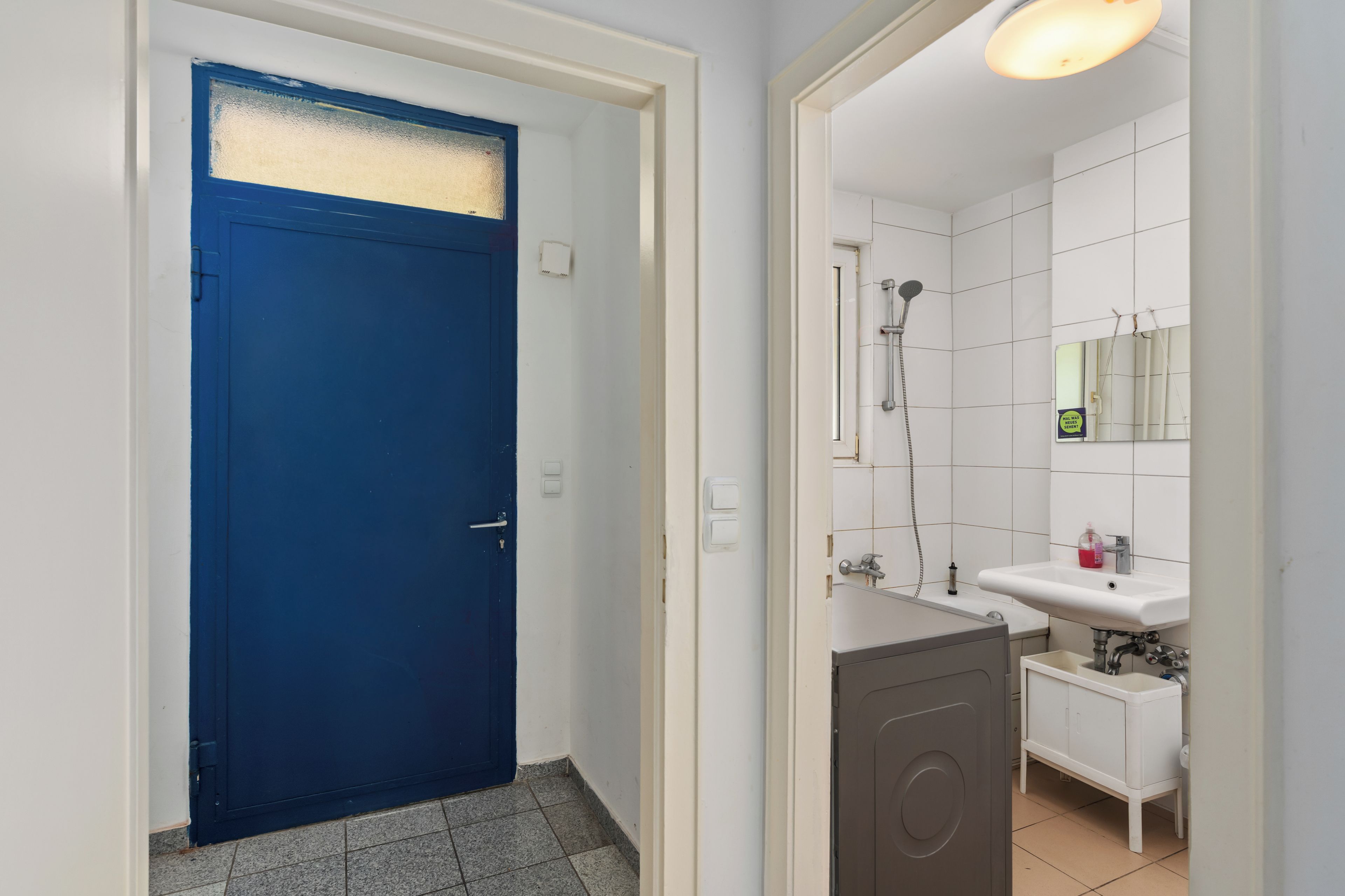 Een badkamer met douche, wastafel en spiegel.