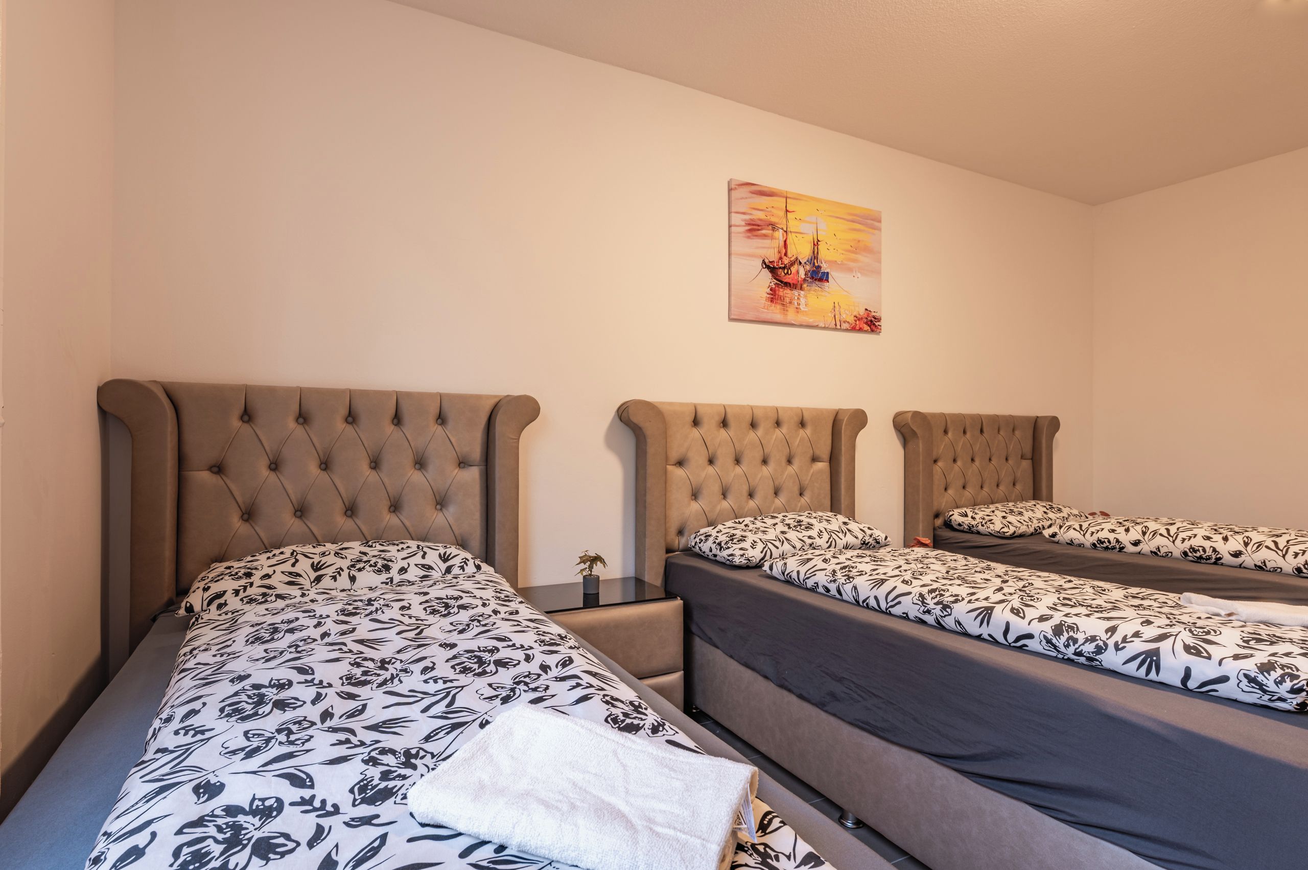 Une chambre d’hôtel avec deux lits, chacun doté d’une tête de lit capitonnée et de draps à motifs floraux.
