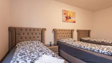 A hotel room with two beds, each with a tufted headboard and floral-patterned bedding.