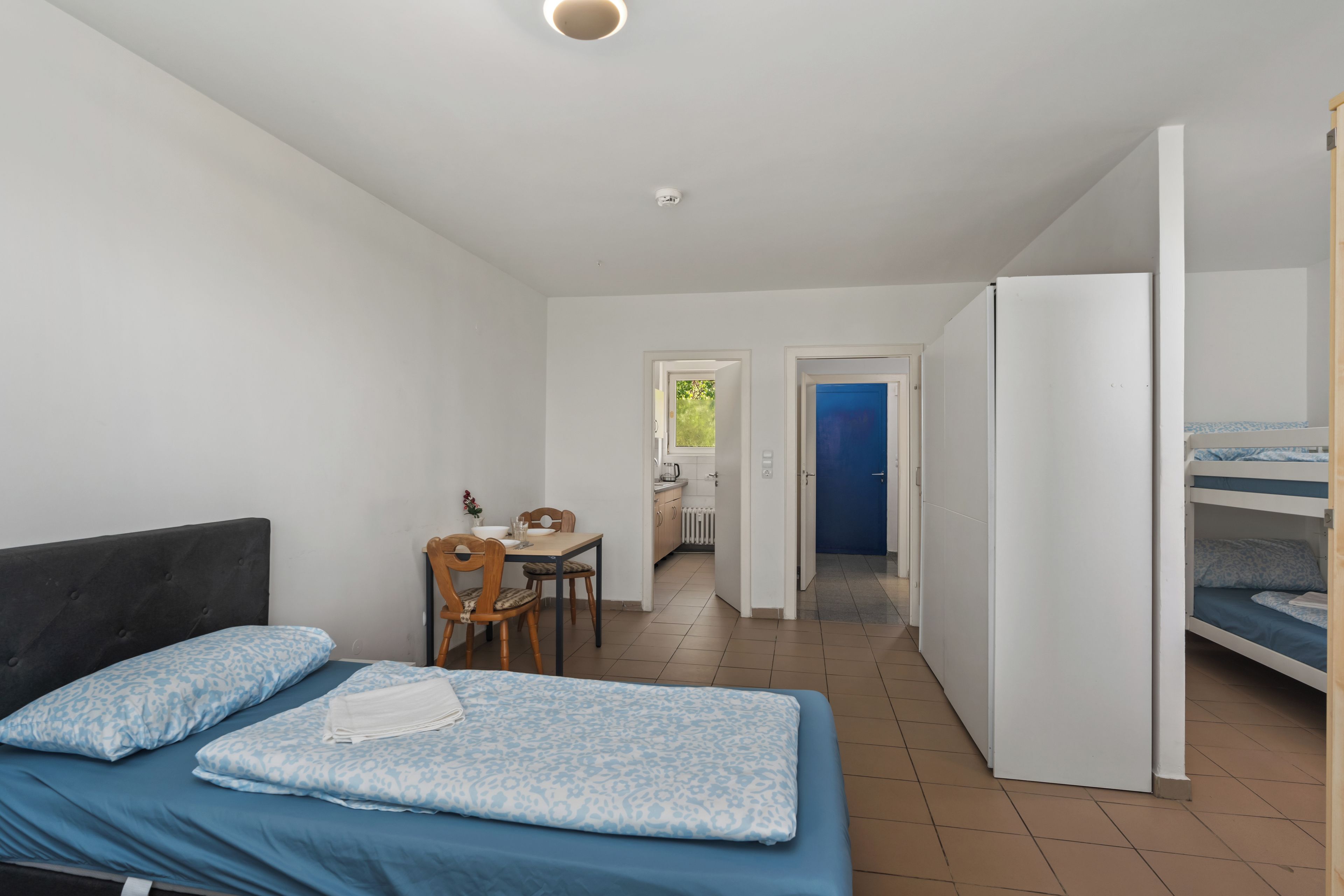 Een slaapkamer met een bed, een bureau en een kitchenette.