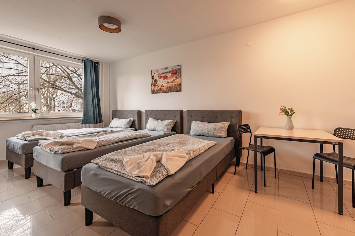 Habitació d'hotel amb dos llits, una taula de dinar, cadires, un ram de flors i un quadre a la paret.