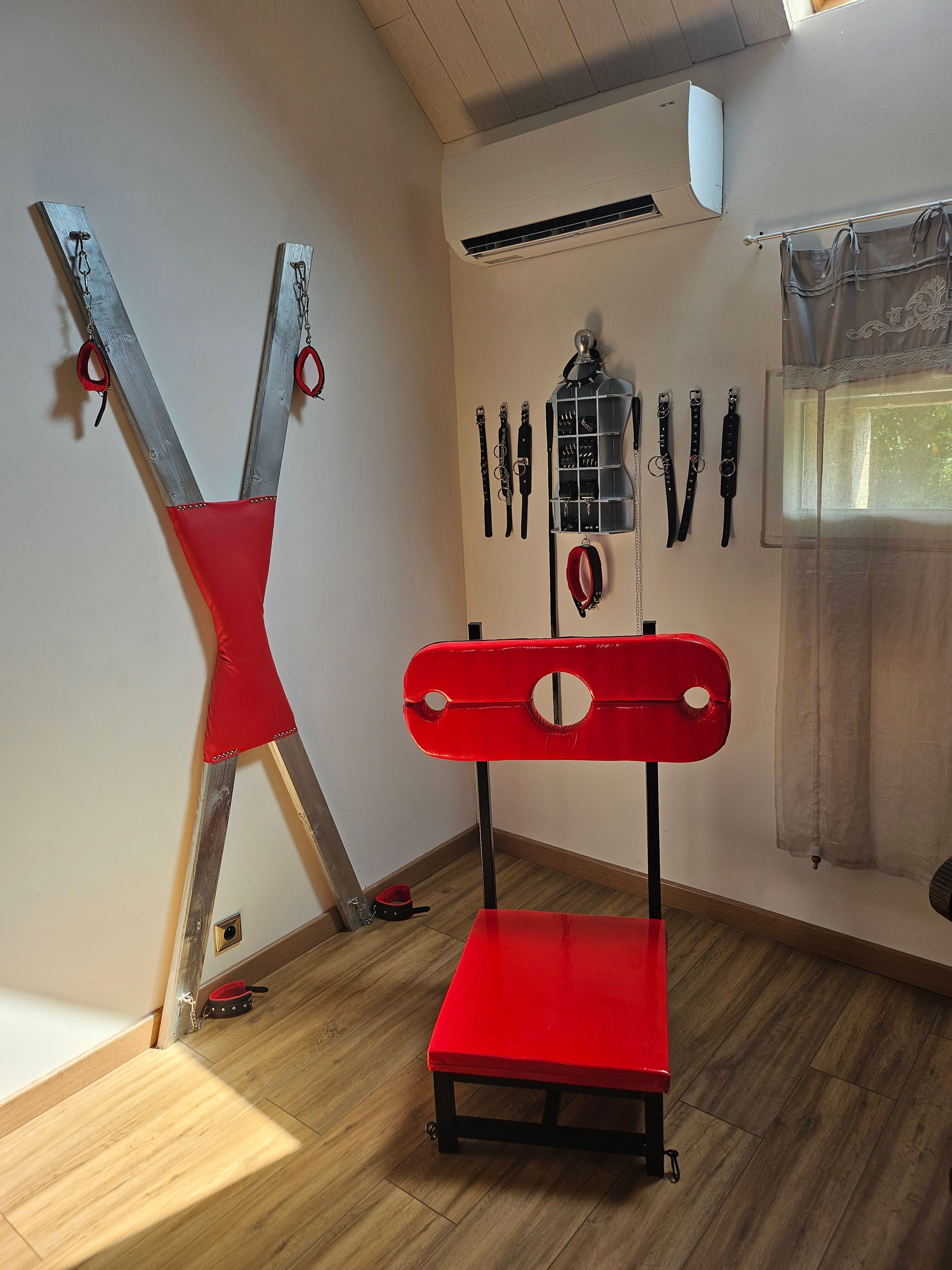 Una habitación con una silla roja, un banco rojo y un aire acondicionado instalado en la pared.