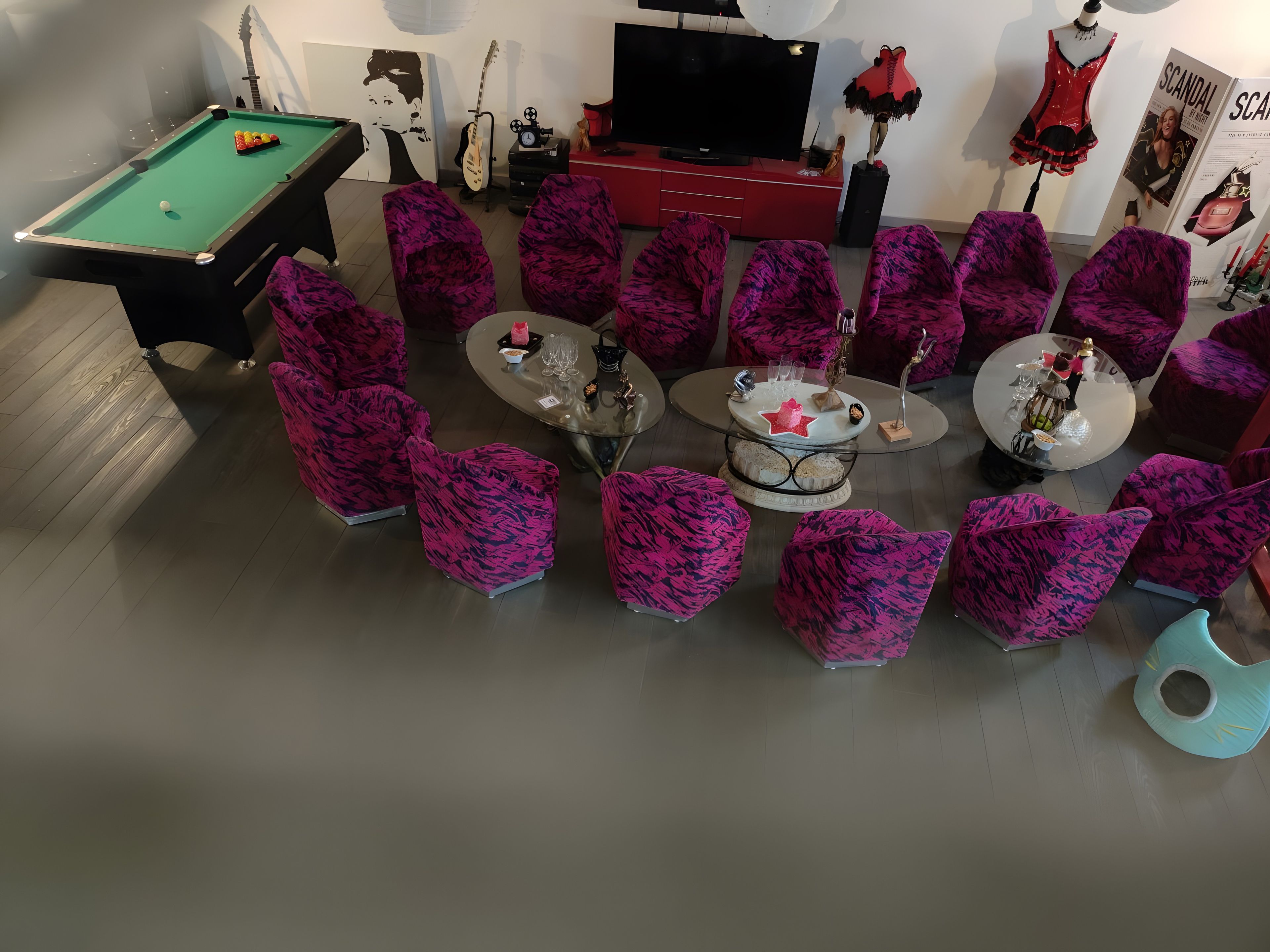 Une pièce comprenant une table de billard, un téléviseur et un espace salon circulaire avec une table centrale.