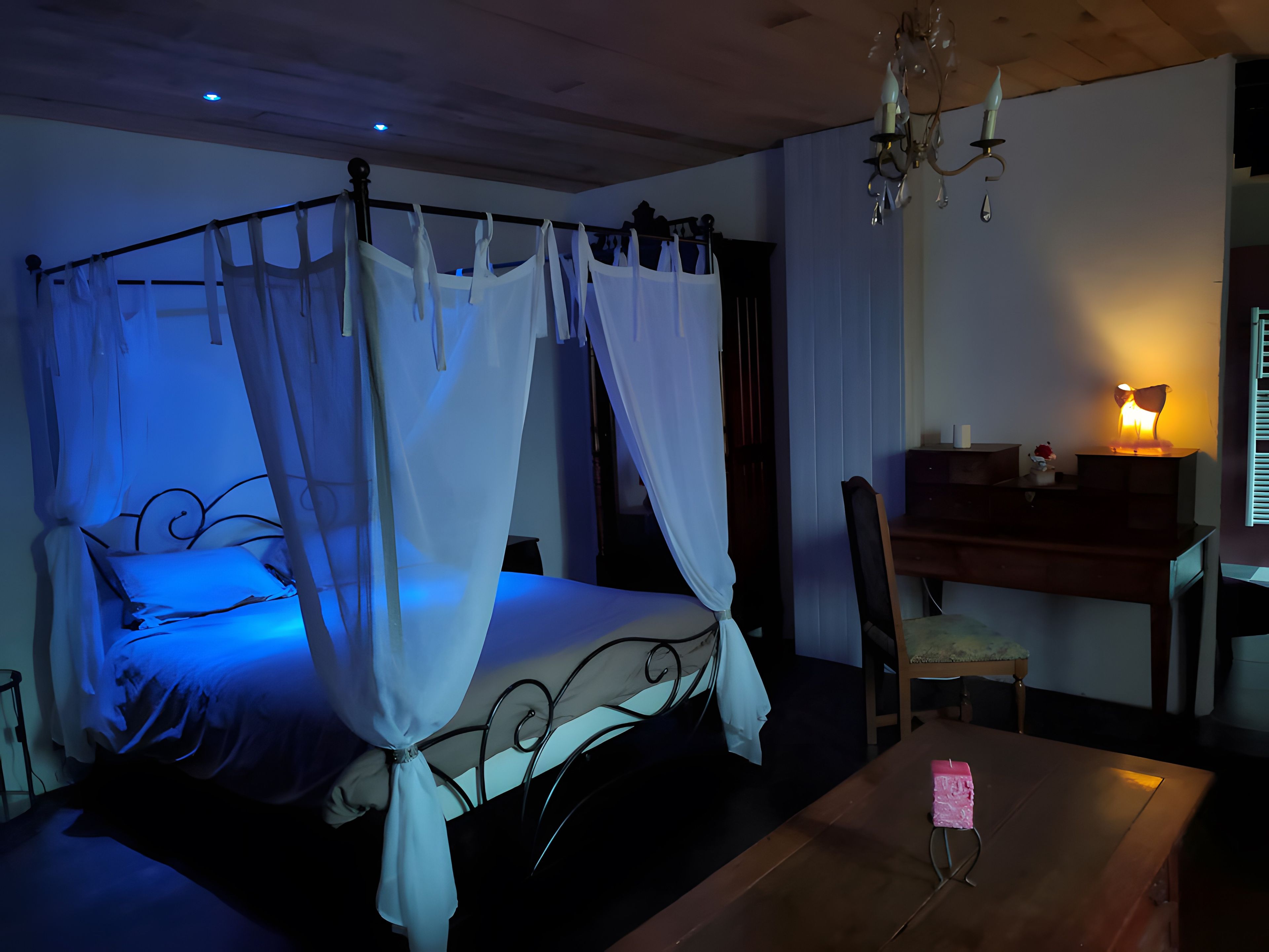 Une chambre à coucher avec un lit à baldaquin, un bureau, une chaise et une table sur laquelle se trouve un objet rose.