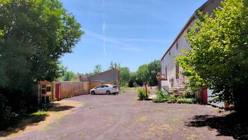 A gravel driveway leading to a white car parked in front of a building with a red door.