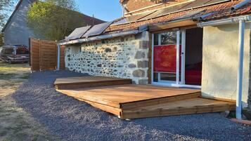 A house with a stone exterior, a wooden deck, and solar panels on the roof.